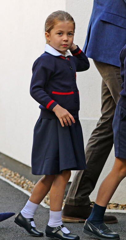 小公主身穿深藍色校服裙、一件深藍色紅間紋毛衣、白色襪及黑色皮鞋