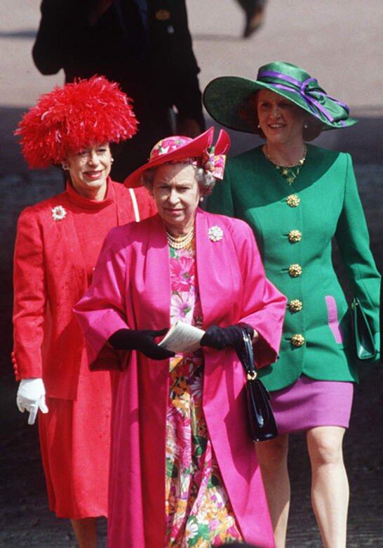 紫色絲帶亮麗點綴翠綠色闊邊帽，即使莎拉站在紅噹噹的英女皇身後，她