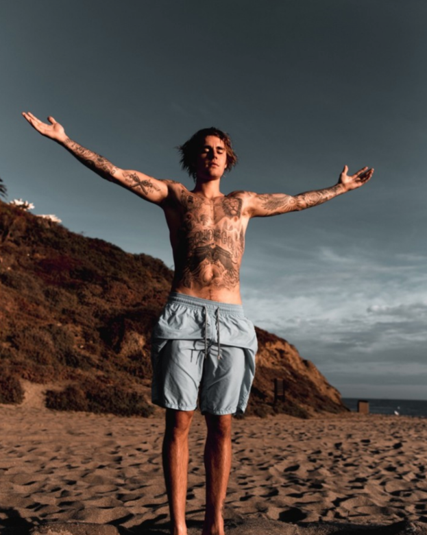 Justin Bieber整個上半身都紋滿了紋身，下身只簡單穿上淺藍色沙灘褲，已經性感
