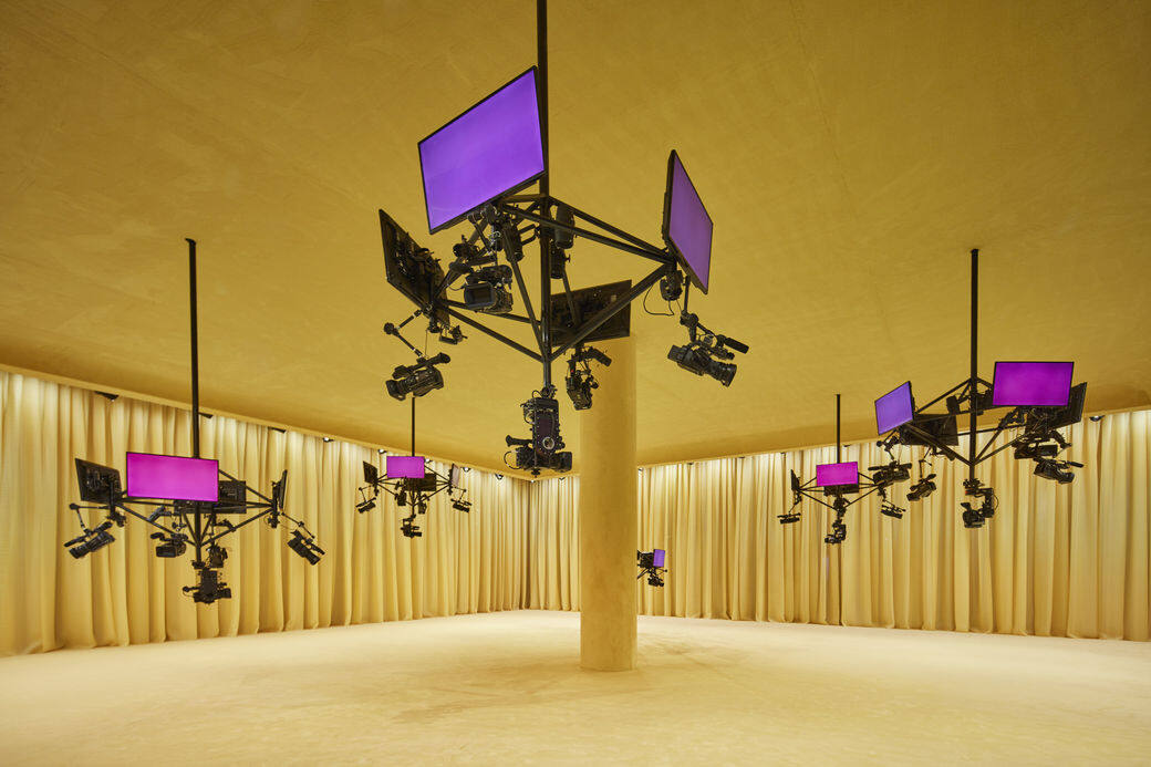騷場環境由Prada老拍檔OMA/AMO構思，天花懸掛著如吊燈般的屏幕和攝影機，既