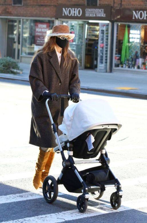 Gigi Hadid帶著她可愛的女兒出門散步時，穿著Mango的咖啡色長板格紋大褸，配上