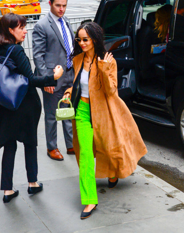 作為一位時尚Icon，Zoë Kravitz從不迴避鮮豔的色彩，大膽穿著螢光青綠色長褲，搭