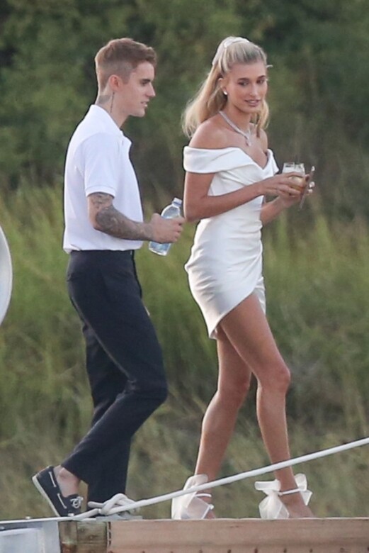 Hailey Bieber身穿V領的露肩白色連身裙，腳踩著可愛的蝴蝶結高跟鞋，婚紗造型