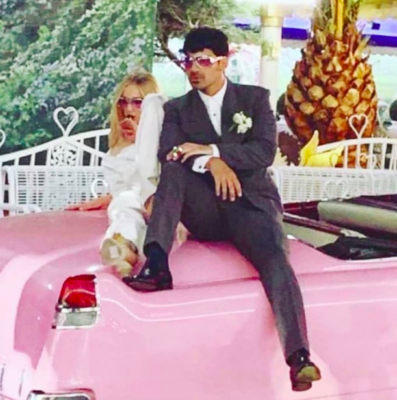 不按常規地，一對新人在婚禮上在粉紅色的Cadillac上拍照，然後穿着禮服跳進