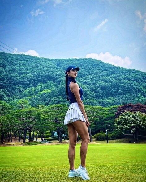 白色高爾夫裙褲的百褶有助加強鄭雅琳臀部的豐滿感，搭配藍色樽領入