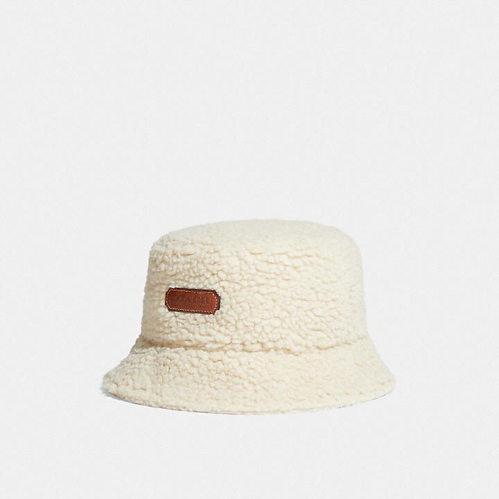 Coach的漁夫帽採用充滿冬日感的白色羊羔毛，並綴上品牌的Logo，配搭出這款