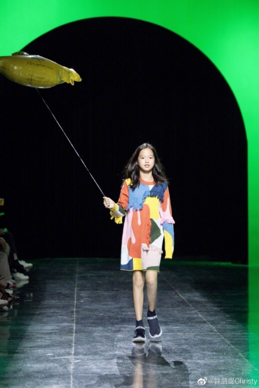 Jaden穿上彩色拼布連身裙，手牽著一個氫汽球走在舞台上，十分可愛。