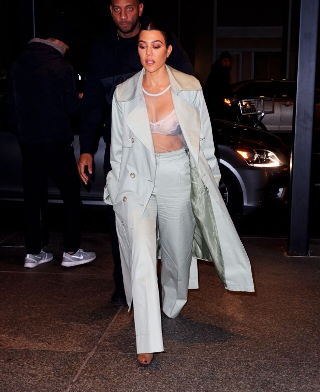 Kourtney Kardashian身穿貼身的白色透視上衣，露出蕾絲內衣，配上帥氣風褸外套及高腰