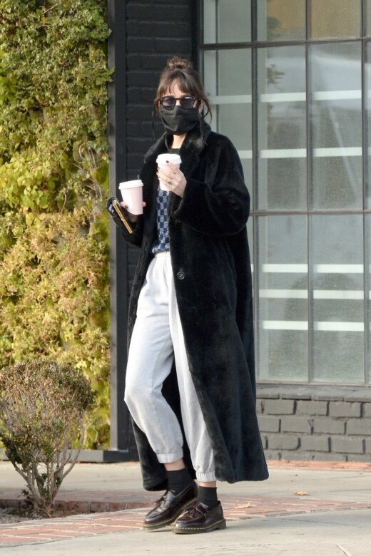 Dakota Johnson以超長版型的絨面大褸混搭淺灰色棉褲，再配搭Dr. Martens的Adrian鞋款，展現