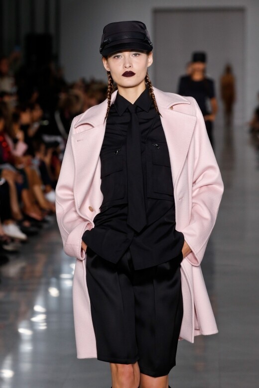 全黑的三件式西裝套裝外搭粉紅色的大褸，中和剛強視覺上的古板，為女