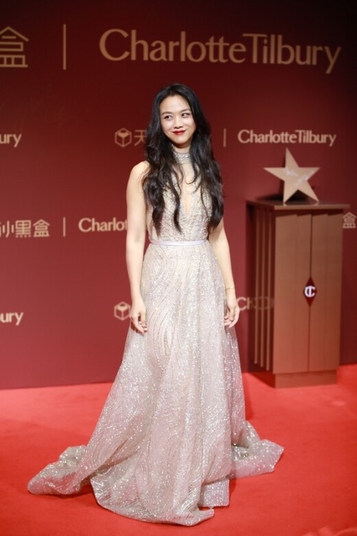 去年湯唯於上海出席美妝品牌活動時，穿上銀色閃閃深V長裙，配上大紅