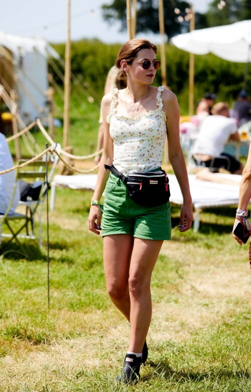 私底下的Emma Corrin回歸24、5歲的英國少女打扮，碎花背心、綠色短褲配腰包和
