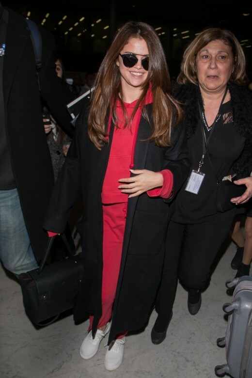 Selena Gomez一身紅色hoodies打扮，加上一件黑色大衣，強烈的色彩大膽有自信。